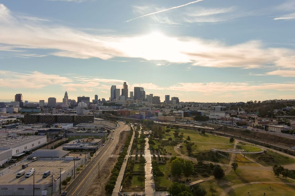 Une vue sur les toits d’une ville, avec un gratte-ciel imposant, une autoroute et un parc agrémenté d’un monument circulaire.