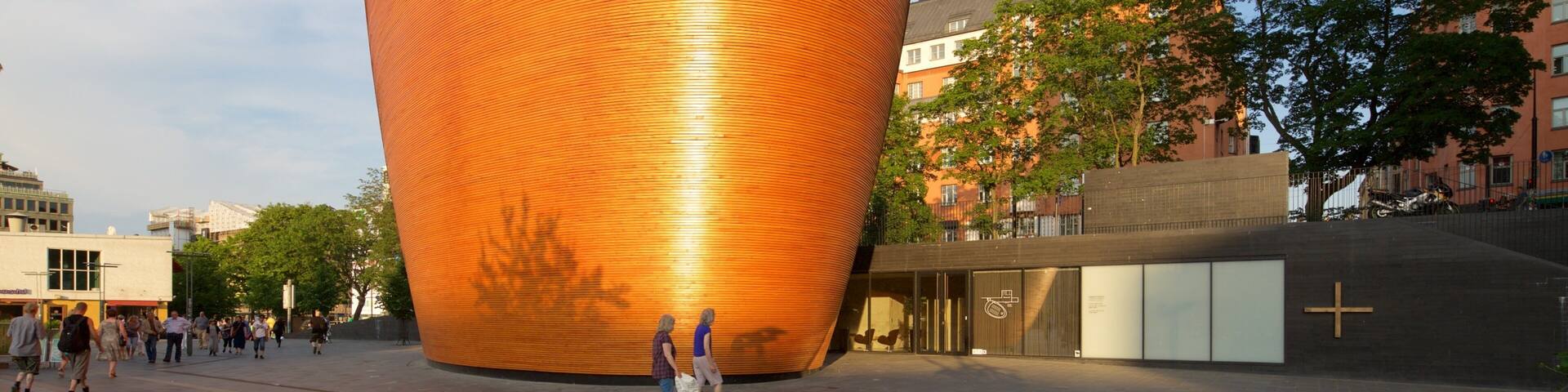 A large, orange, cylindrical building with a seagull perched on top.