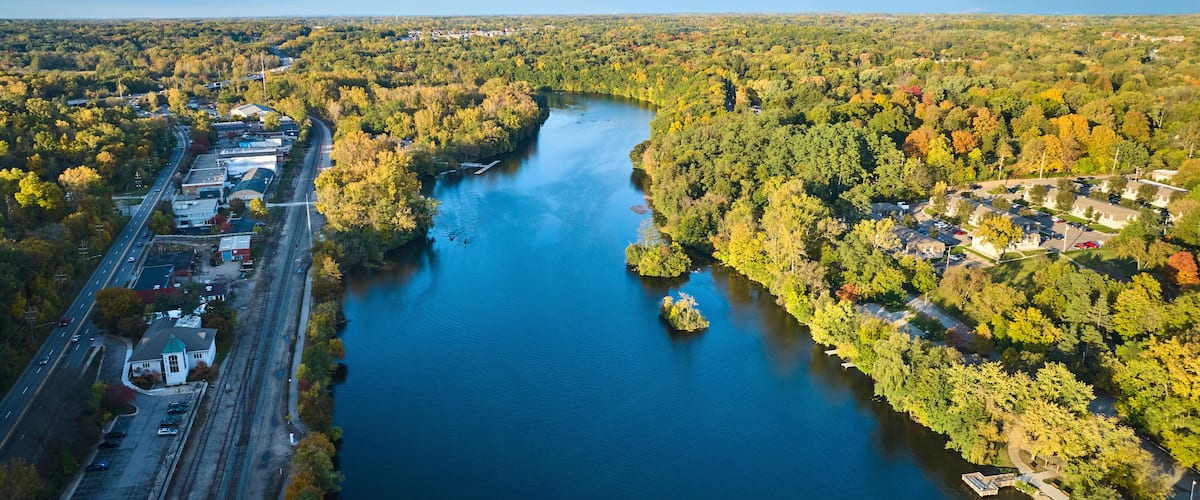 Aerial View of Serene River and Autumnal Trees in Small Town