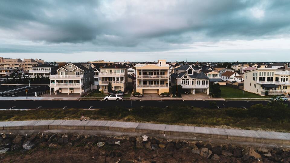 A residential area with multi-story houses, a road, and a rocky embankment.