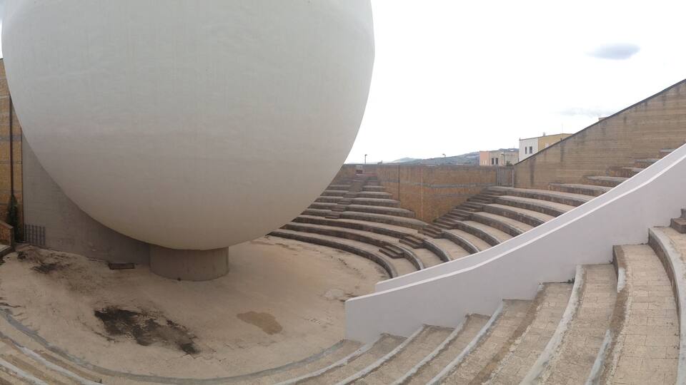 A spiral staircase leading up to a large white spherical structure in an outdoor setting.