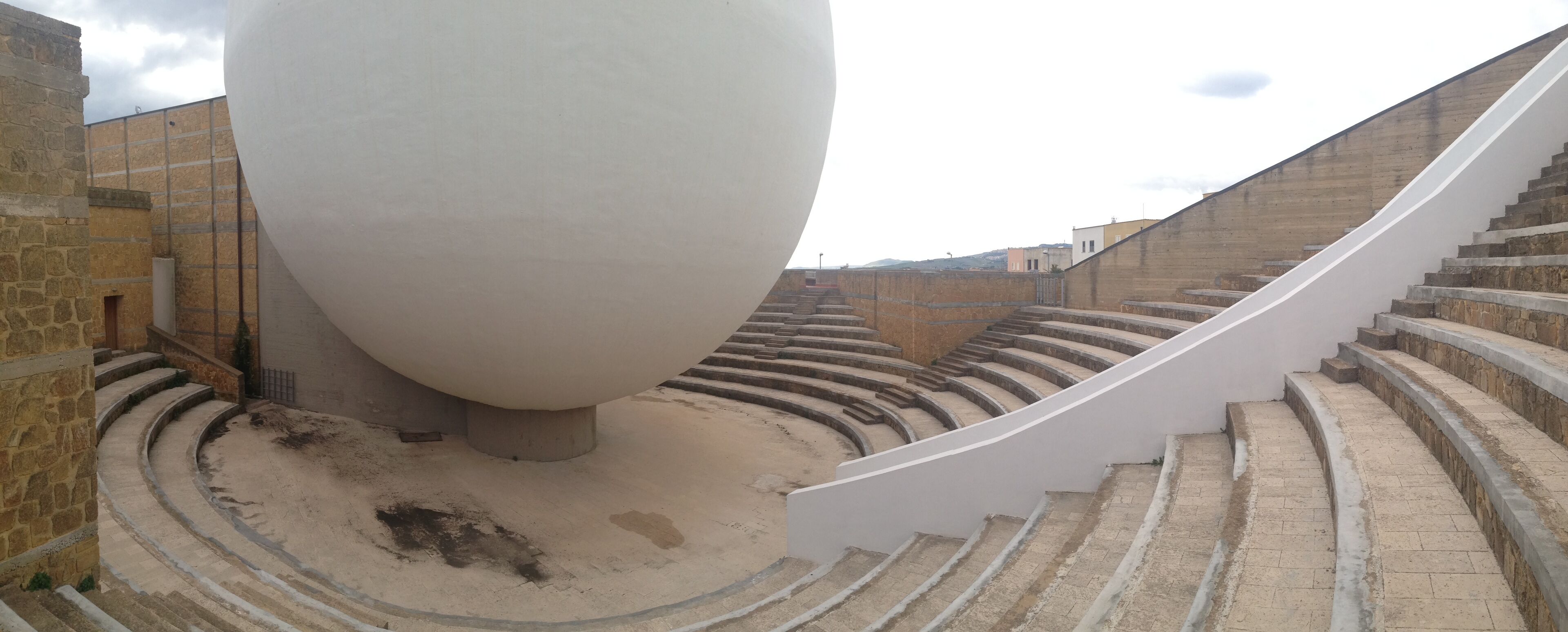 A spiral staircase leading up to a large white spherical structure in an outdoor setting.