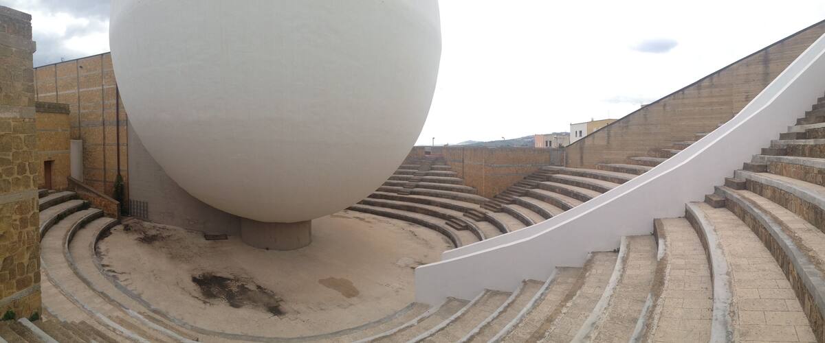 A spiral staircase leading up to a large white spherical structure in an outdoor setting.