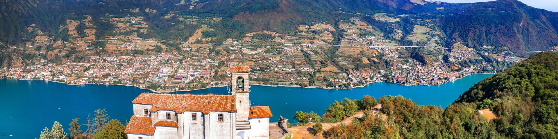 Scenic romantic lakes of Italy - Lago Iseo surrounded by beautiful mountains. Aerial view of small church in top of Monte isola island. Popular tourist attraction