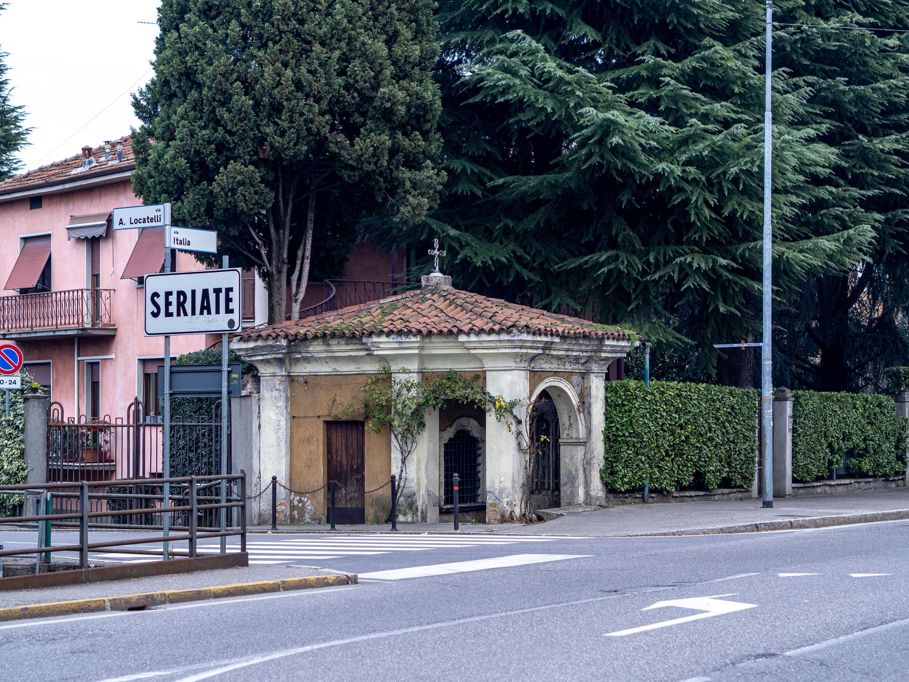 A street corner with a small church, a pink building, and a sign reading "SERIALE."