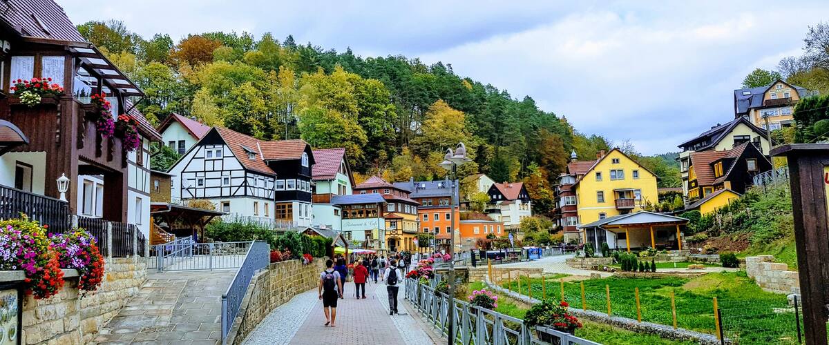 A picturesque village with traditional half-timbered houses, a cobblestone street, and a hillside backdrop.