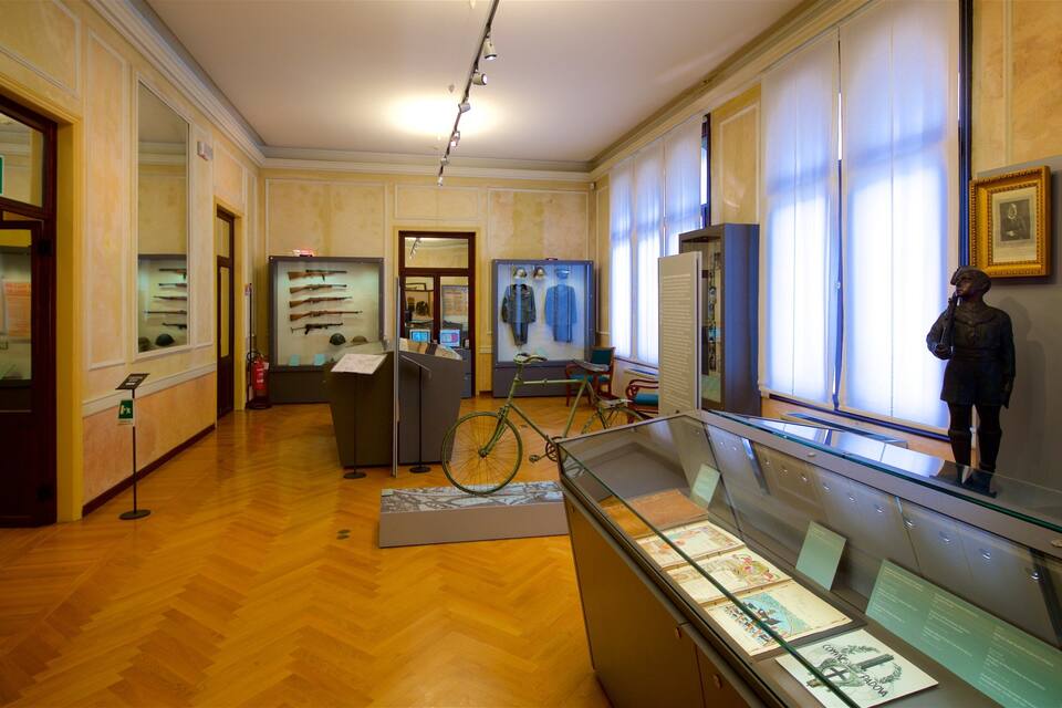L’intérieur d’un musée, avec des planchers en bois, des vitrines et diverses pièces exposées, notamment des fusils, des casques et un vélo.