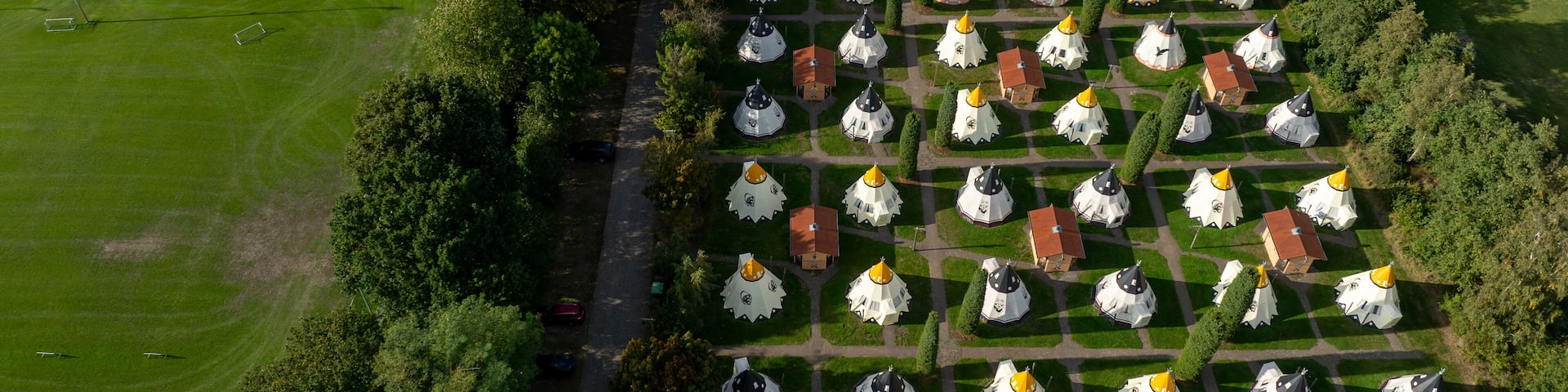 Slagharen, Netherlands - 03 October 2023: Aerial view of the Wigwam Parc's distinctive wigwam-shaped accommodations, a vibrant tapestry of red roofs and white walls amidst lush greenery.