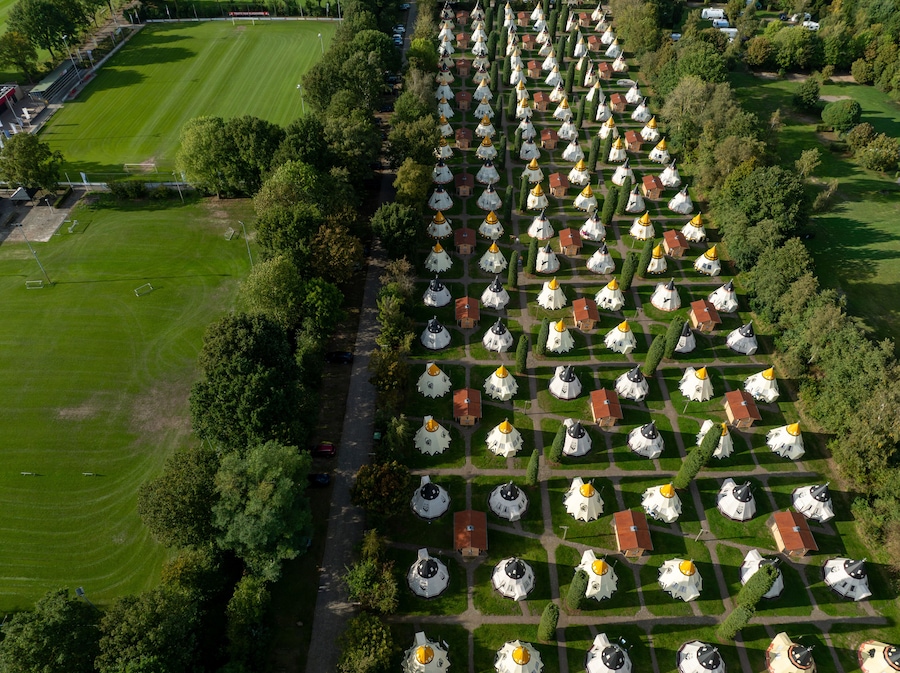 Slagharen, Netherlands - 03 October 2023: Aerial view of the Wigwam Parc's distinctive wigwam-shaped accommodations, a vibrant tapestry of red roofs and white walls amidst lush greenery.