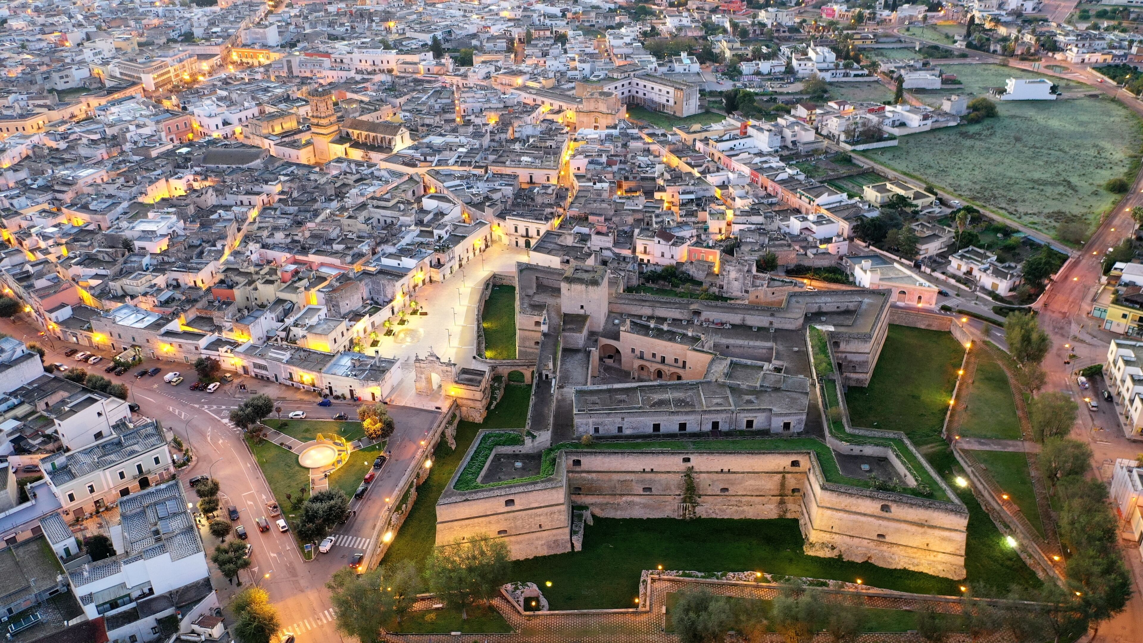 An aerial view of a historic walled city with narrow streets and a prominent fortress.