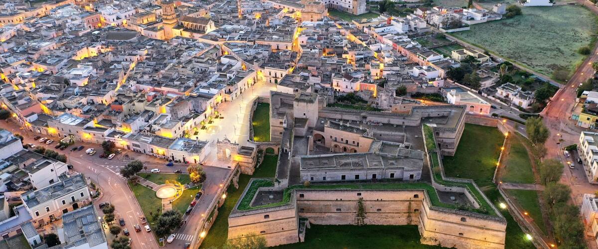 An aerial view of a historic walled city with narrow streets and a prominent fortress.