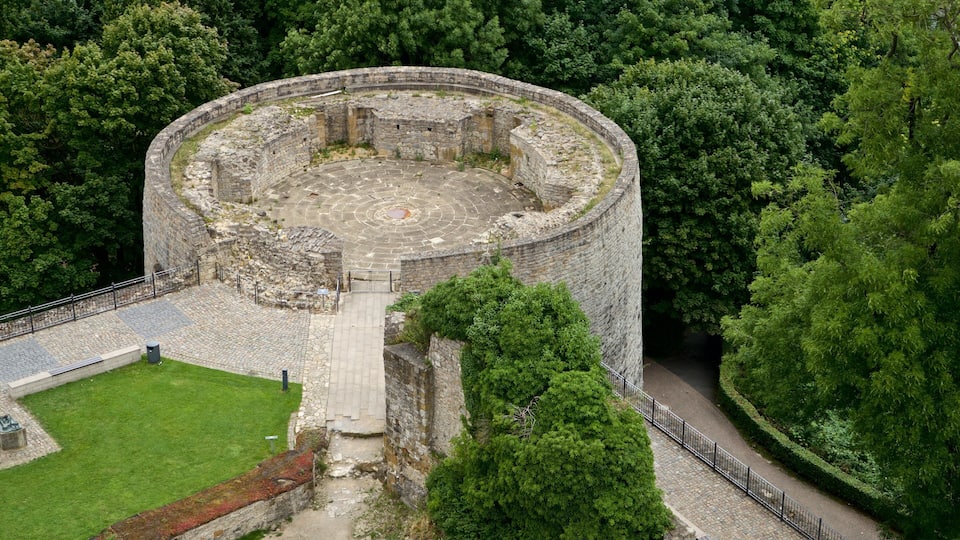 A circular stone structure surrounded by dense forest.