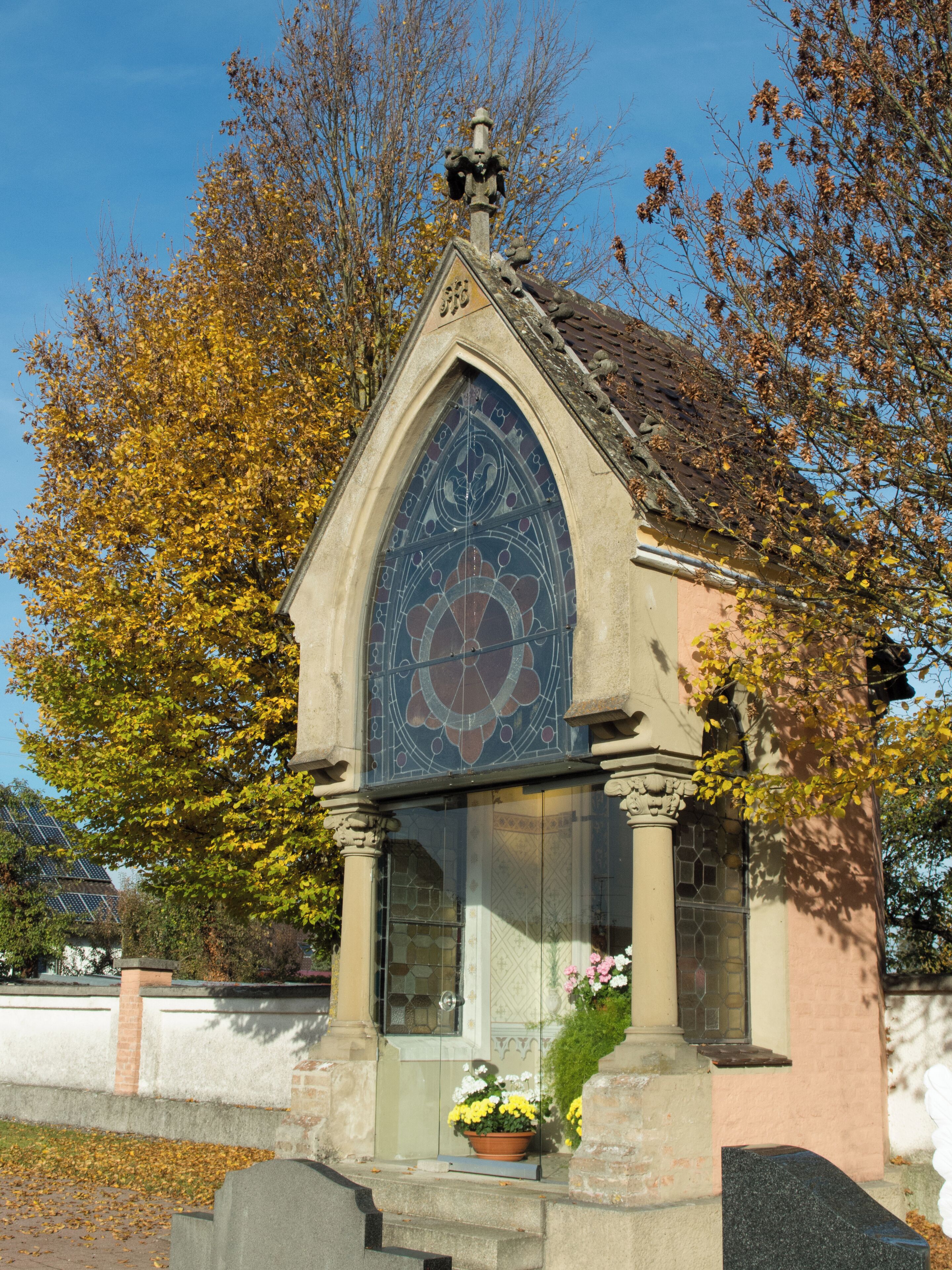A small chapel with a stained glass window and a clock.