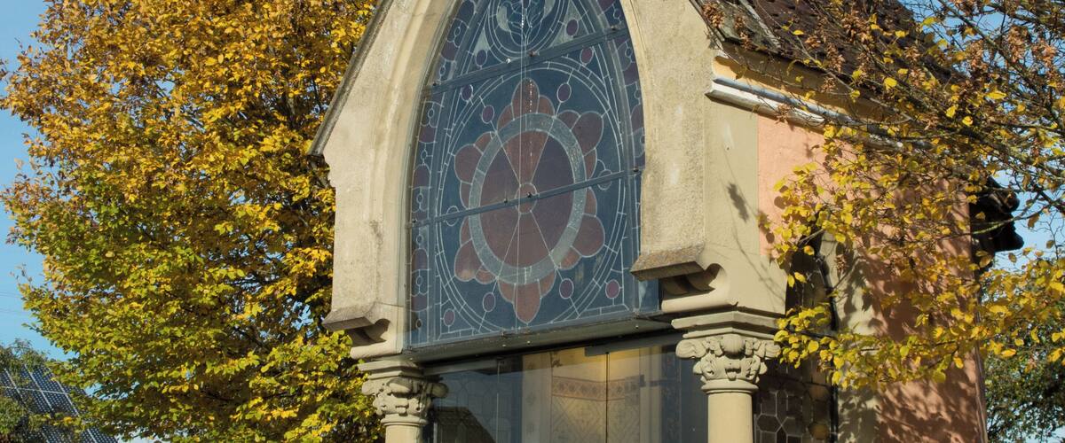 A small chapel with a stained glass window and a clock.