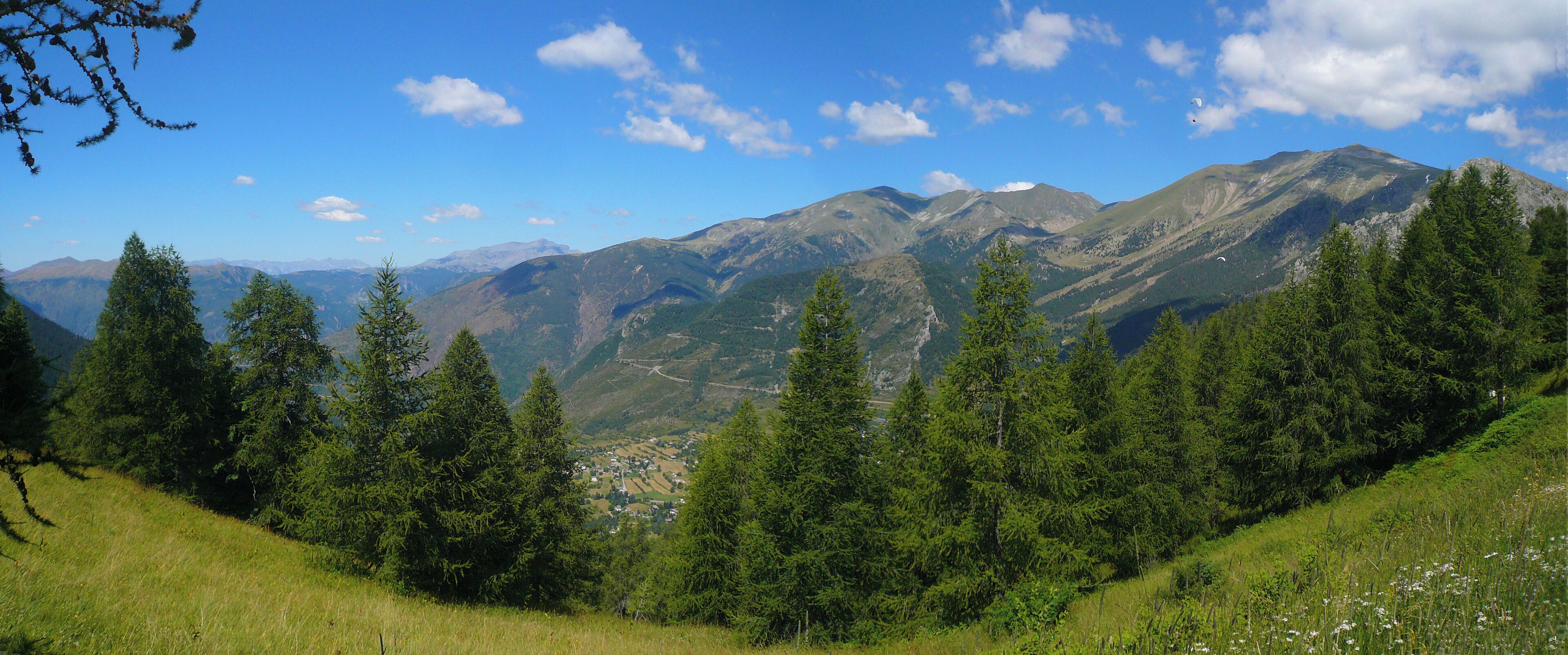 A mountainous landscape with dense forests and a small village in the valley.