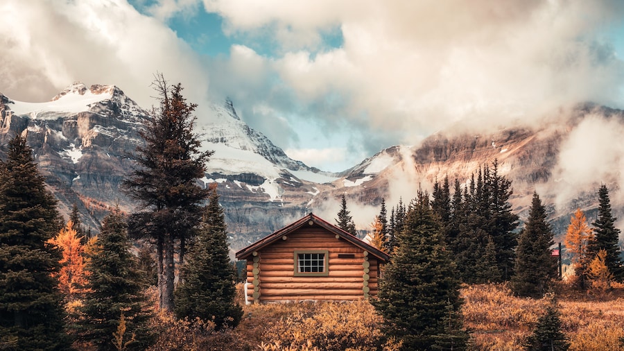 Wooden hut with Assiniboine mountain in autumn forest at provincial park