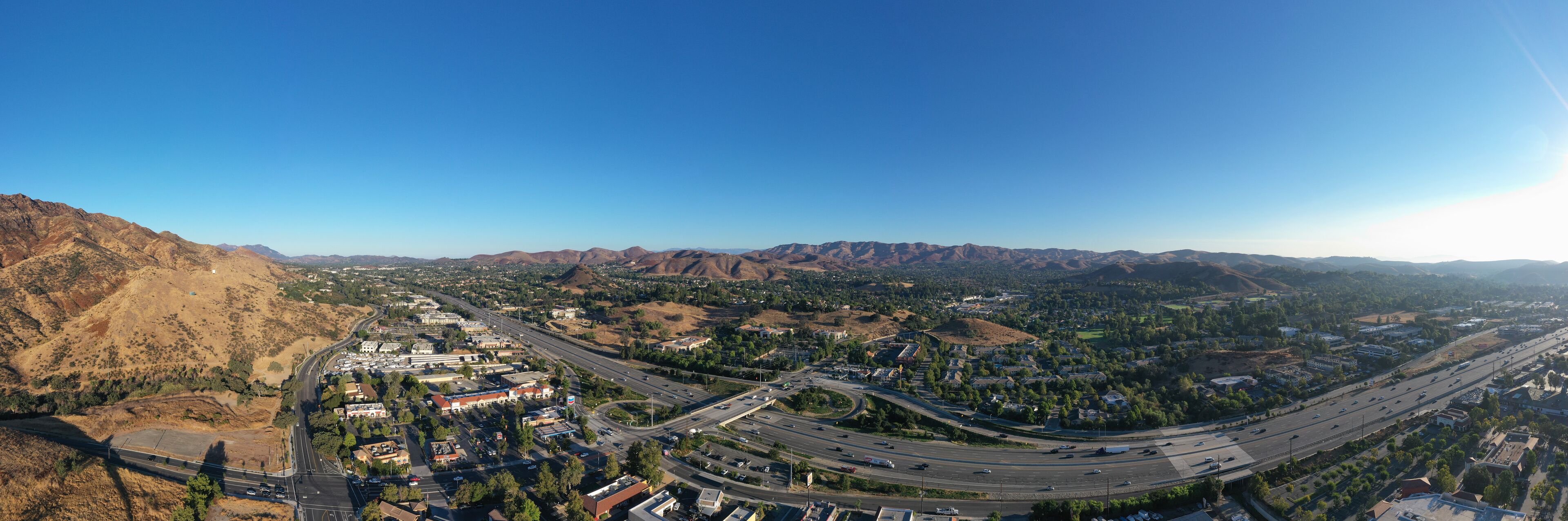A city with a highway and surrounding mountains.