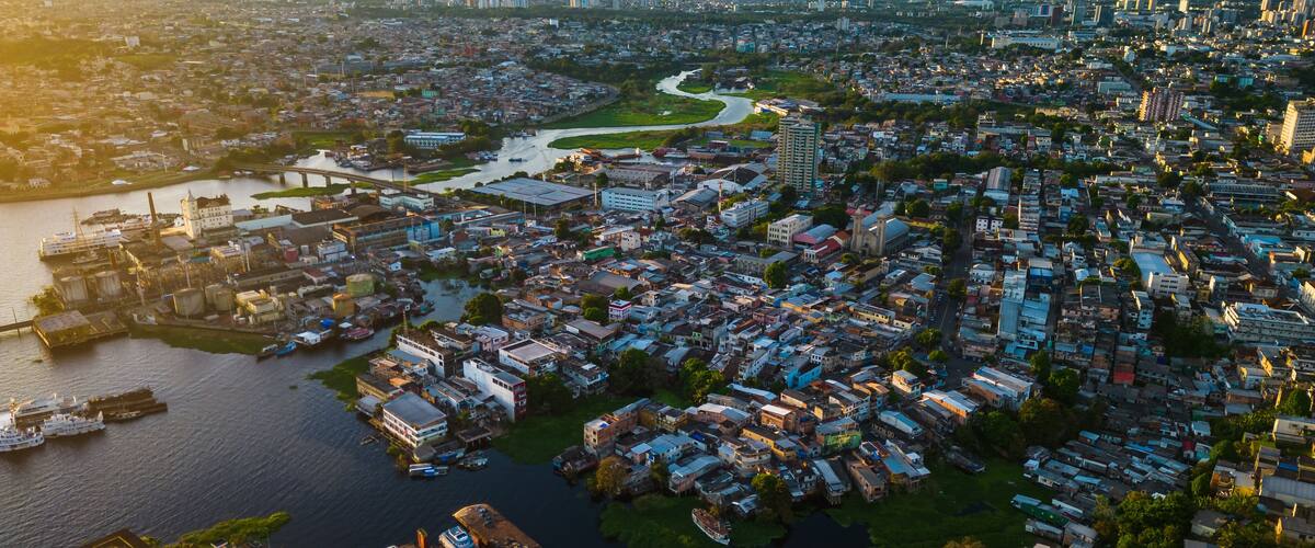 An aerial view of a densely populated city with a river running through it, surrounded by residential and commercial buildings.