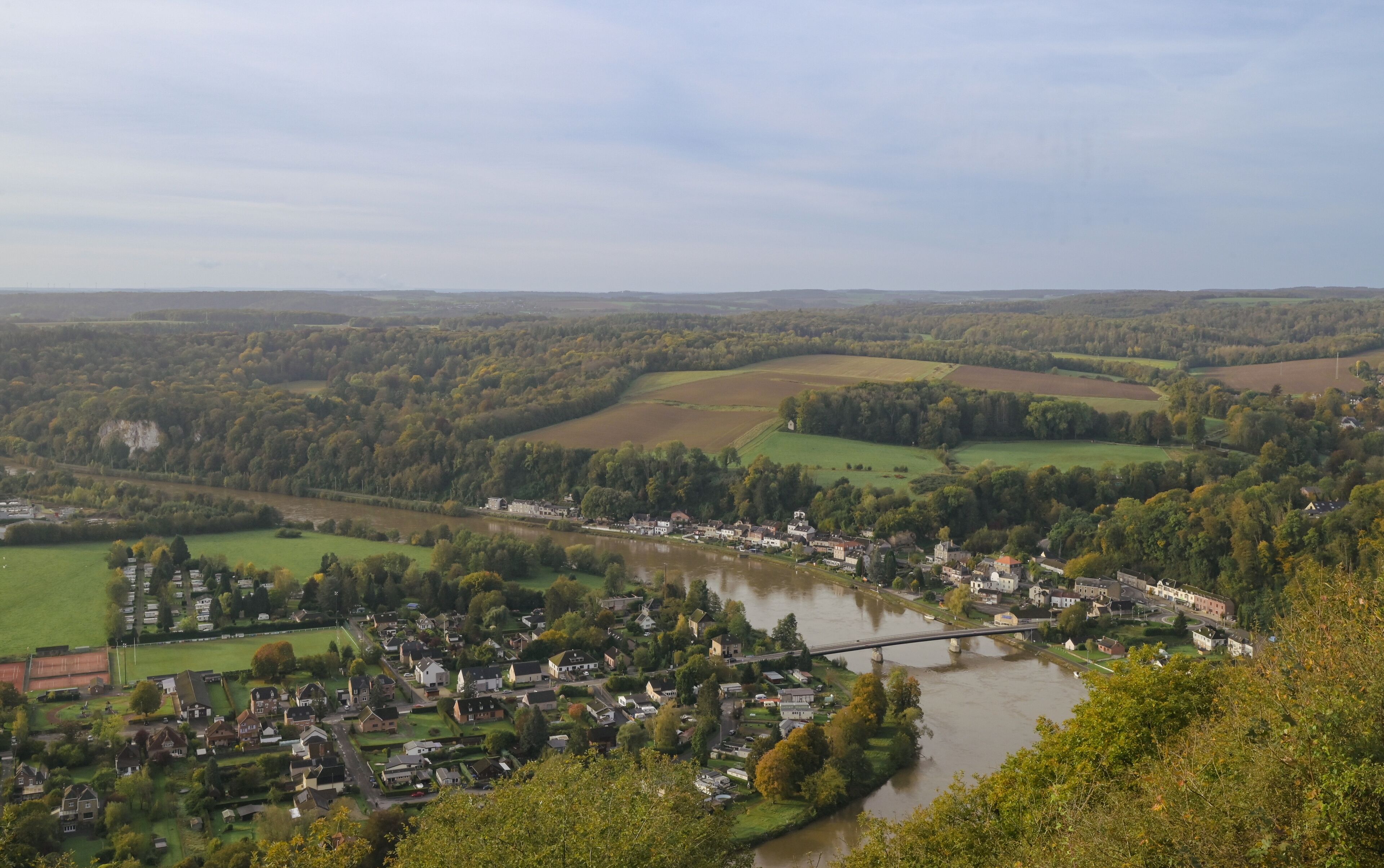 A river flowing through a town surrounded by green fields and hills.