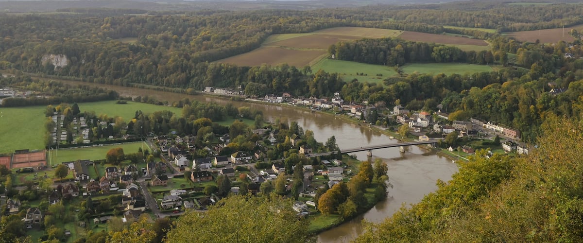 A river flowing through a town surrounded by green fields and hills.