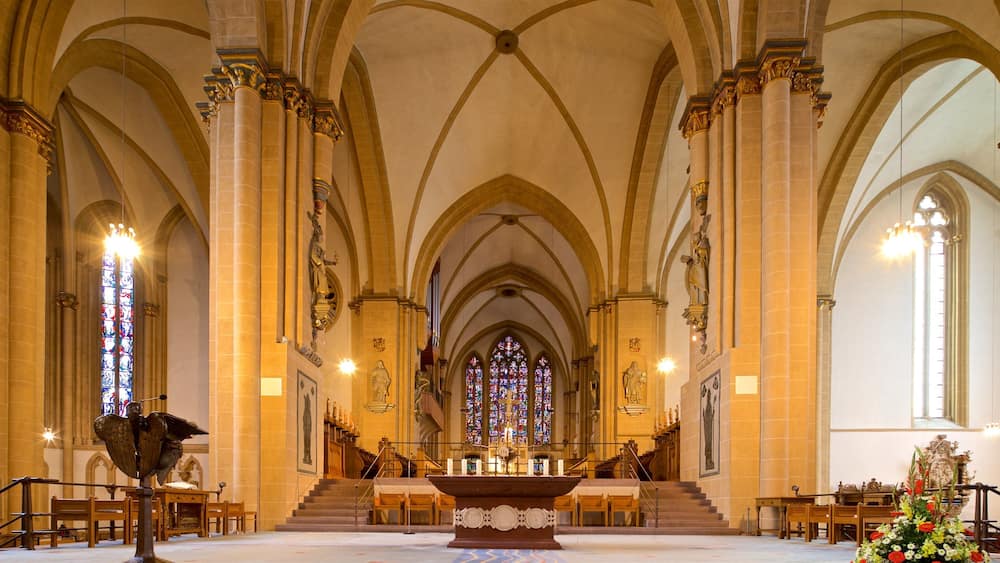 A cathedral interior with high vaulted ceilings, stained glass windows, and a central altar.