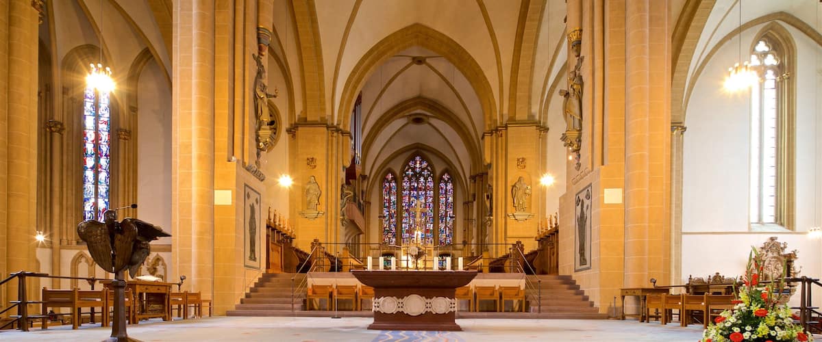 Interior d'una catedral amb altes voltes, finestres de vitralls i un altar central.