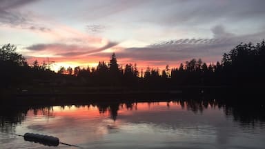 A sunset over a lake with trees silhouetted against the sky.