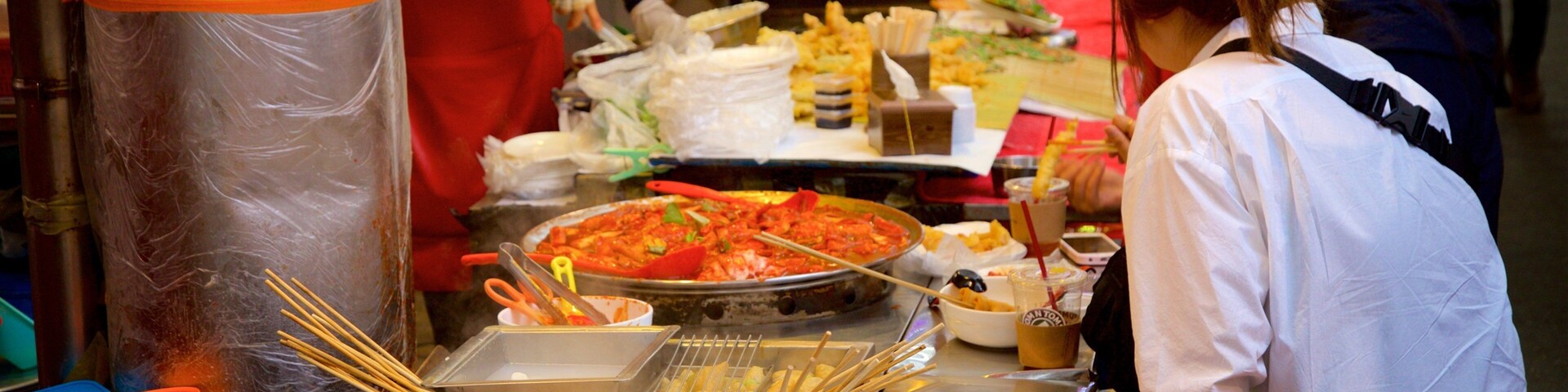 Un puesto de comida con diversos platos, utensilios y una olla grande de comida.