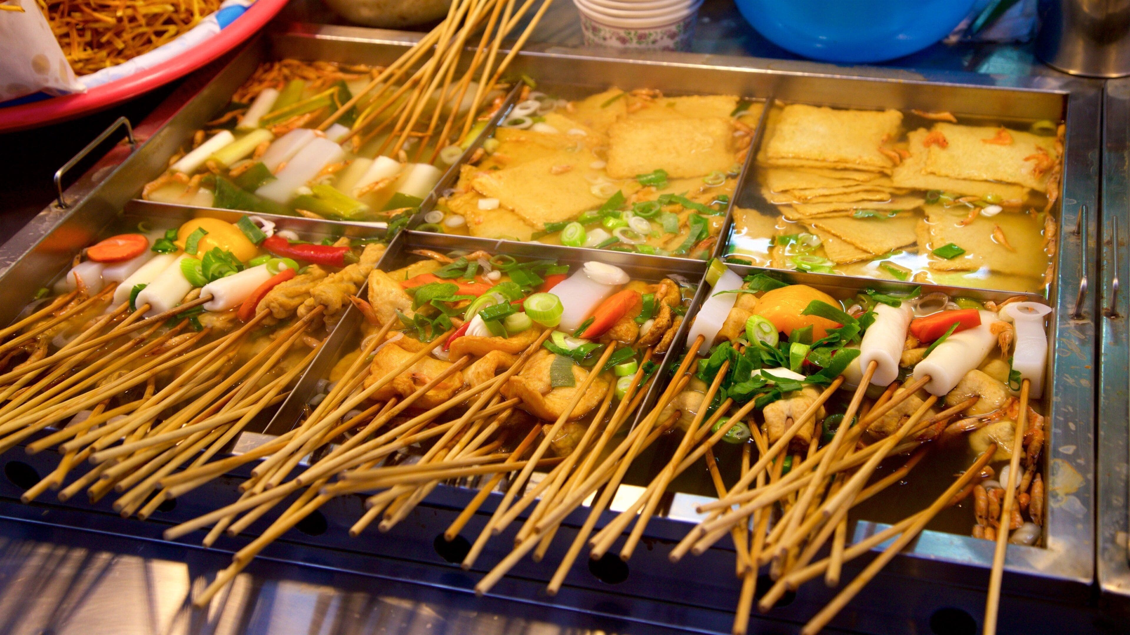 Verschiedene Spieße mit Fleisch und Gemüse in einer Kochvorrichtung.