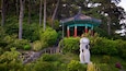 A traditional pavilion with a tiled roof, surrounded by lush greenery and trees.