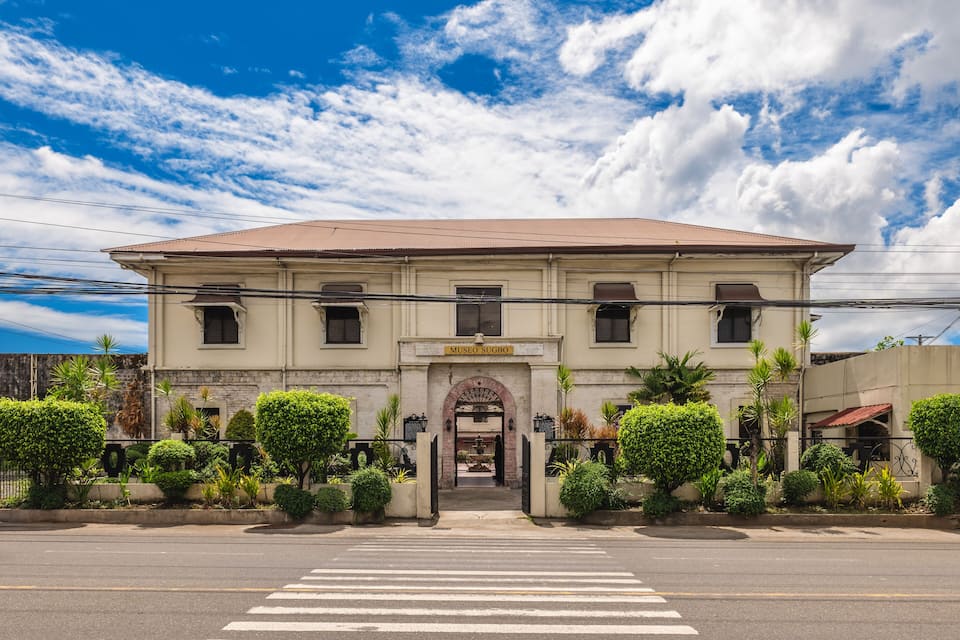 A historic building with a sign reading "Museo Sugbo" and a crosswalk in front.