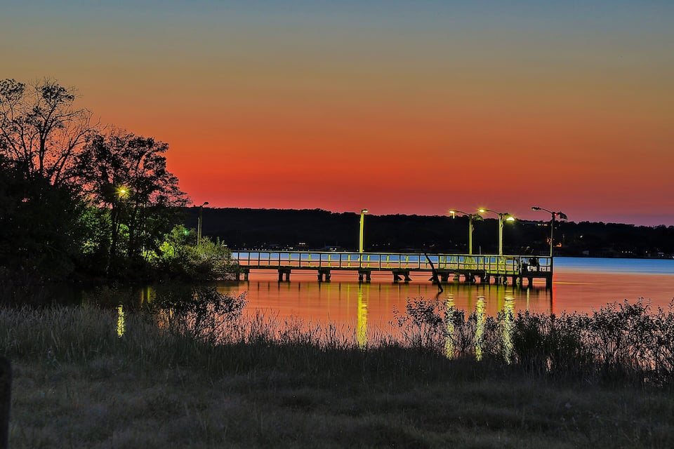 A bridge at sunset with a reflection on the water.