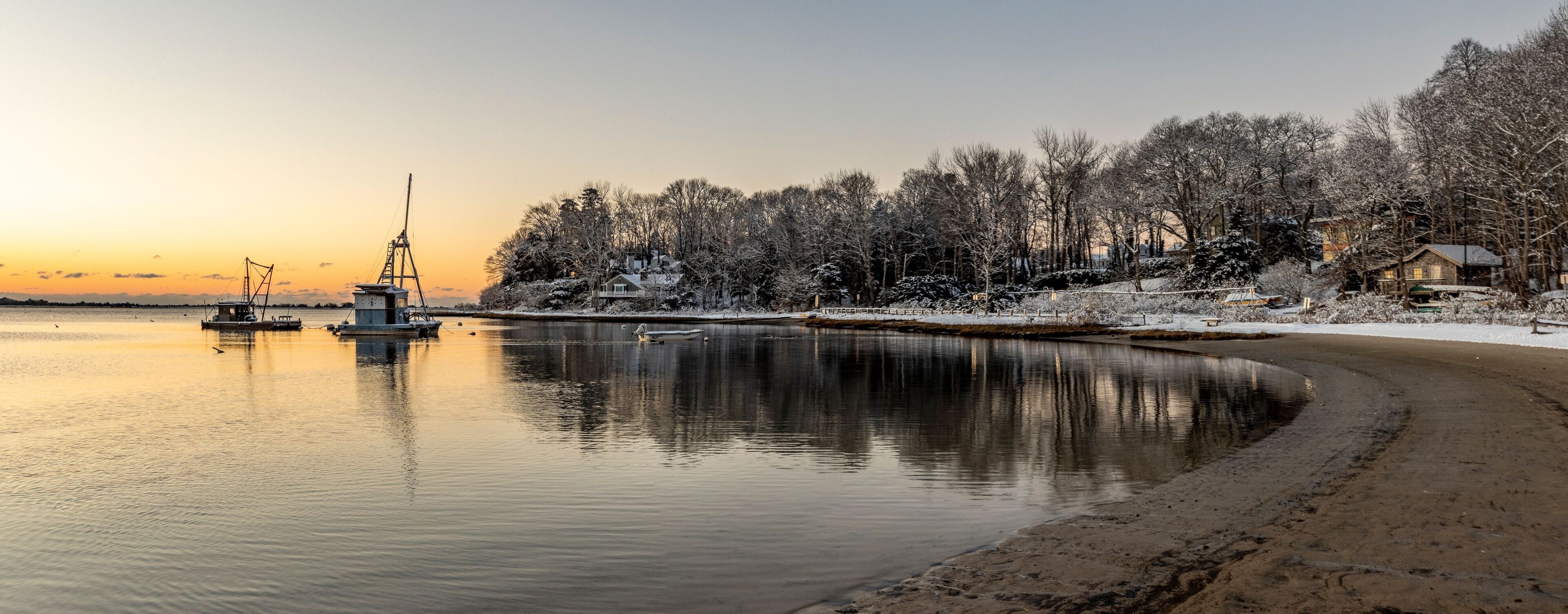 Panoramic shot of Ropes Beach surrounded by snowy trees at scenic sunset in Cotuit, Massachusetts
