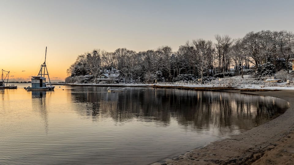 A frozen lake with a dock and a small house in the background.