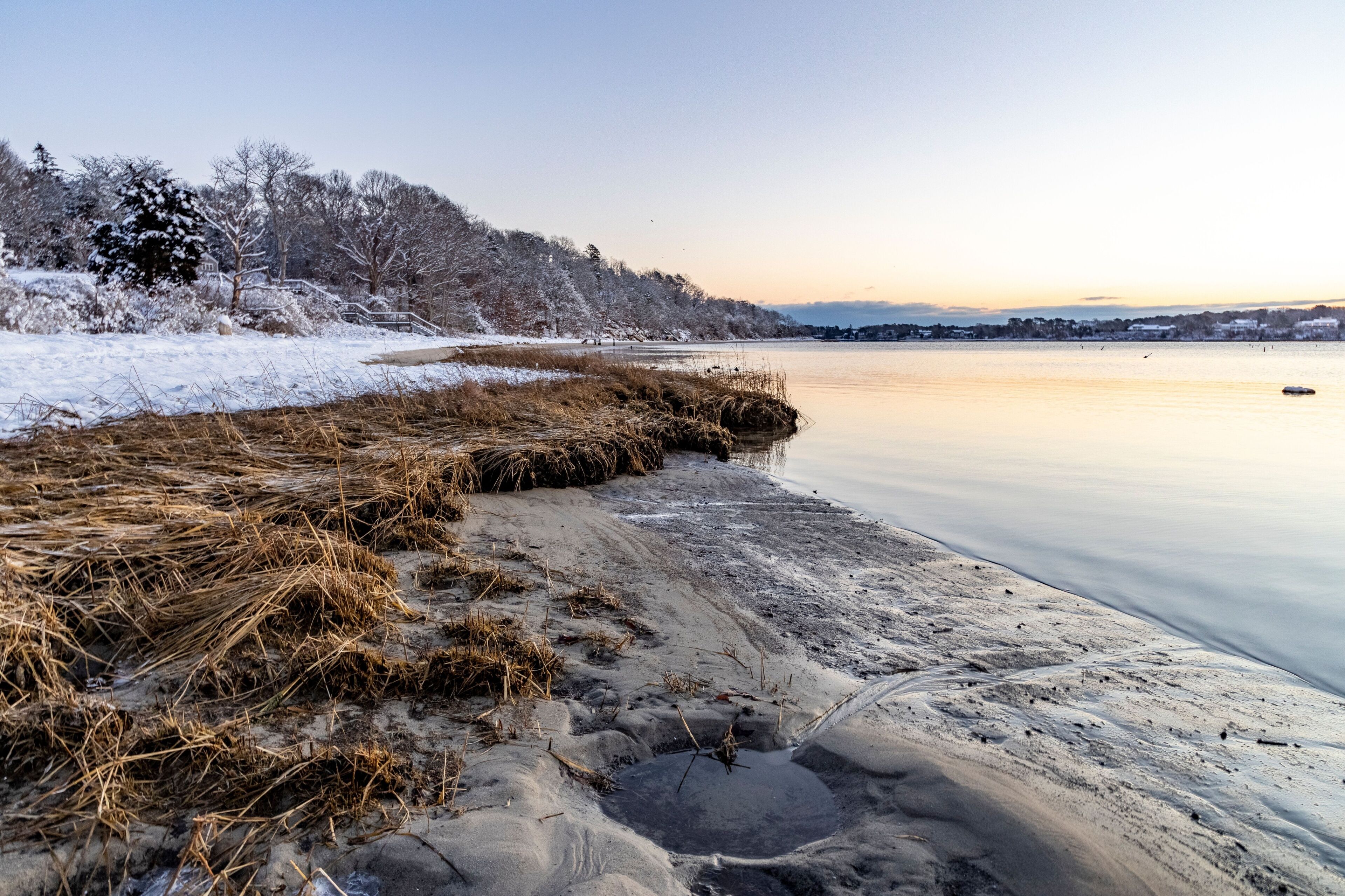 A frozen lake with snow-covered trees and a clear sky.