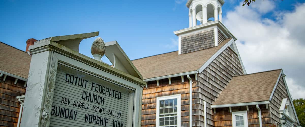 A church sign with worship times and a steeple.