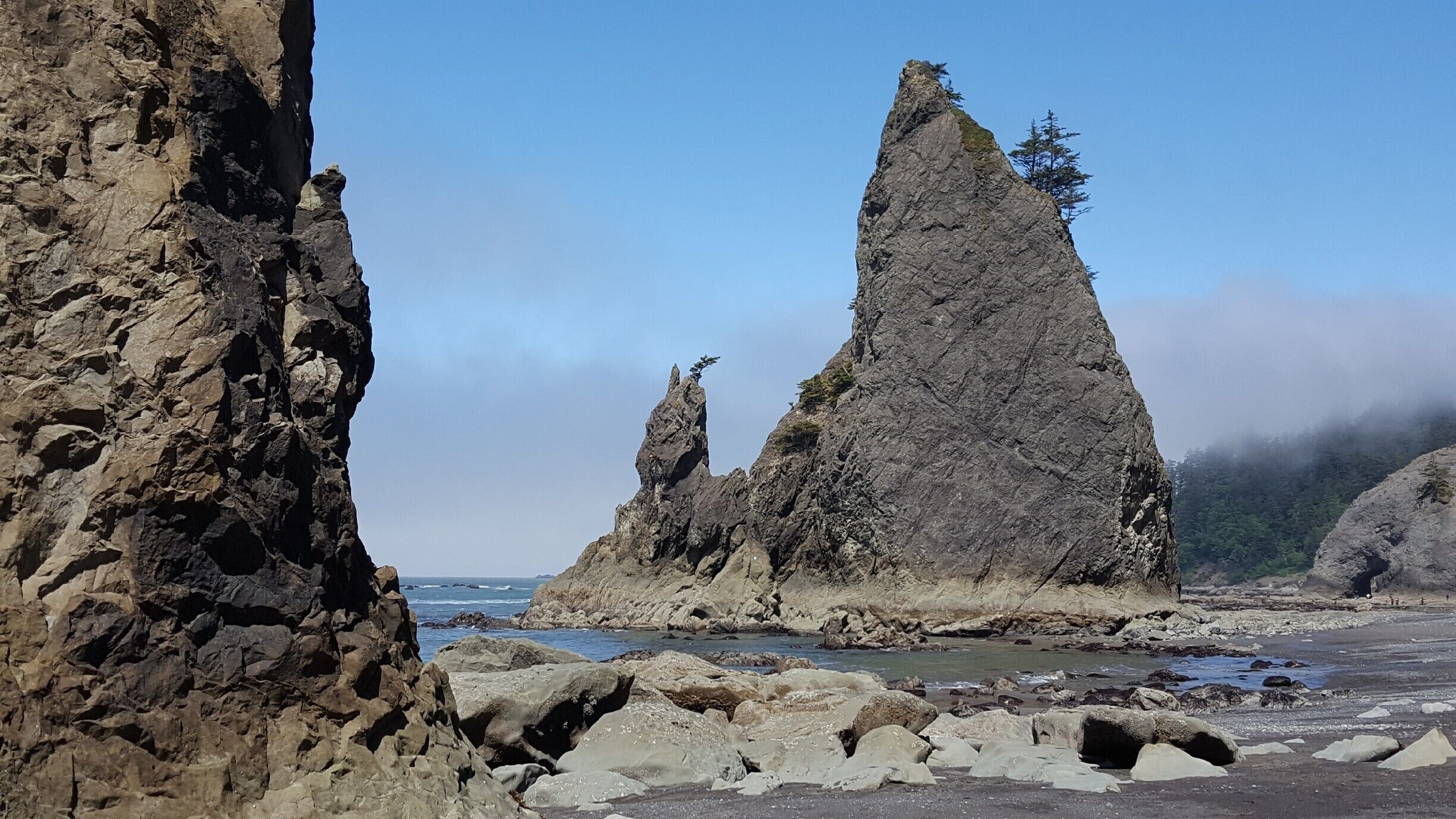 A rocky coastline with prominent rock formations and a clear sky.