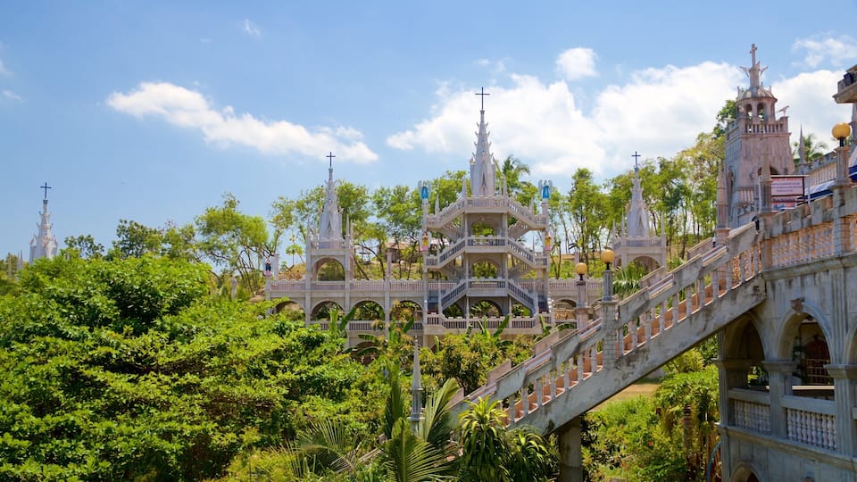 A grand, ornate church with multiple spires and crosses, surrounded by lush greenery.