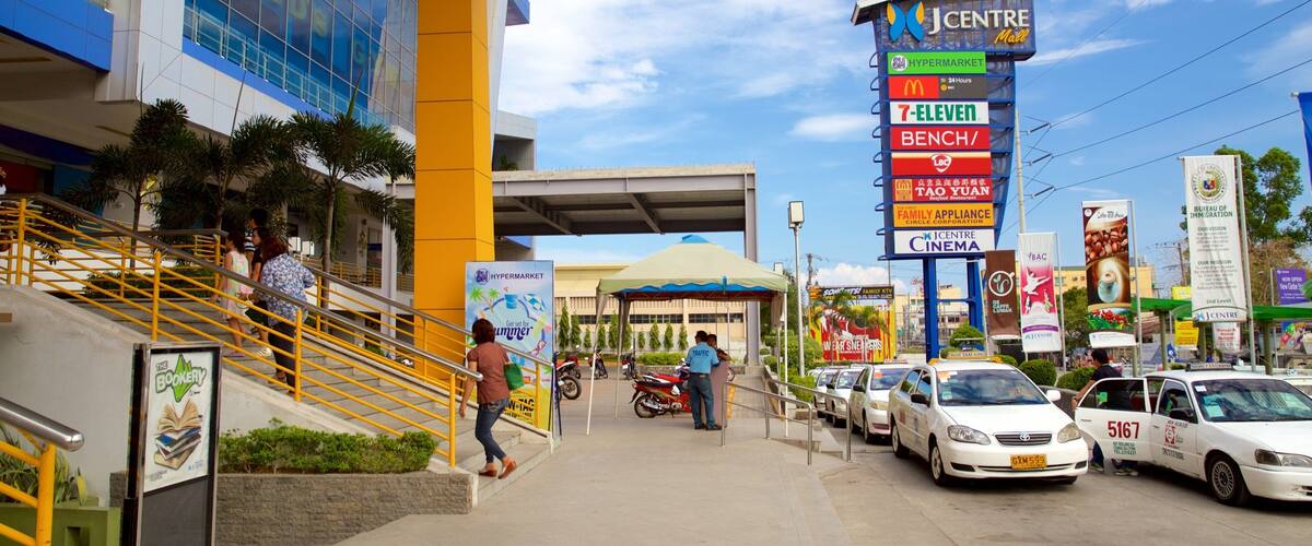 A busy street with a J Centre Mall sign, a Hypermarket, and various other businesses.