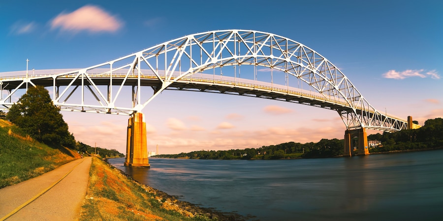 Uma extensa ponte de aço atravessa um rio sob um céu límpido.
