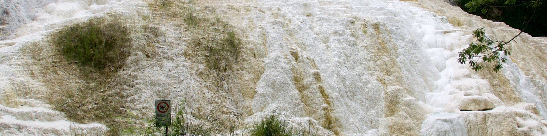 Uma área geotérmica com piscinas de minerais e pessoas nadando.