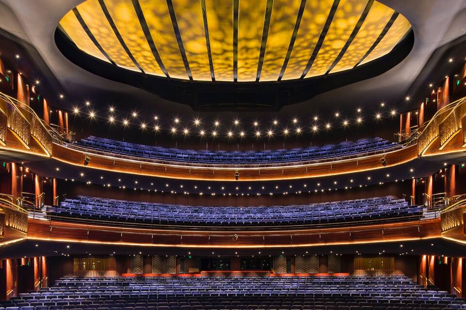 Een auditorium met meerdere niveaus, getrapte zitplaatsen en een centraal podium.
