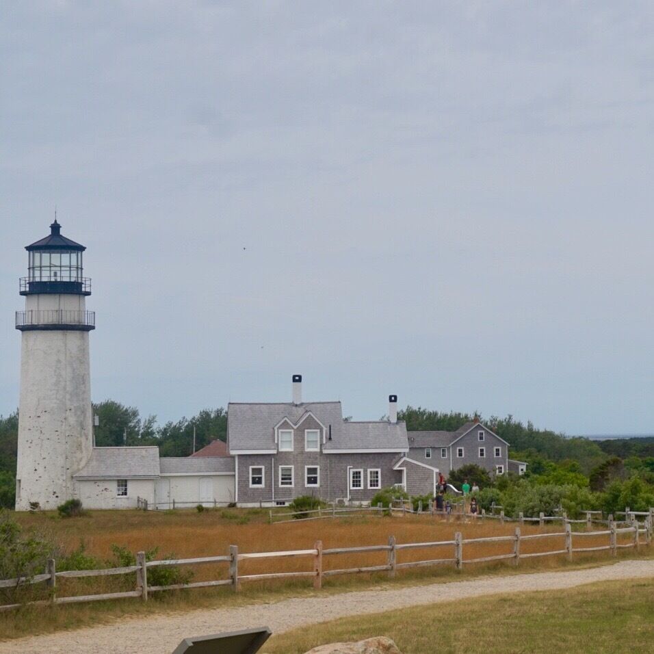 A lighthouse and a large house with a fenced yard.