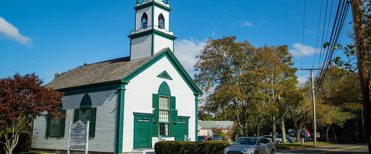 A white church with green trim and a steeple.