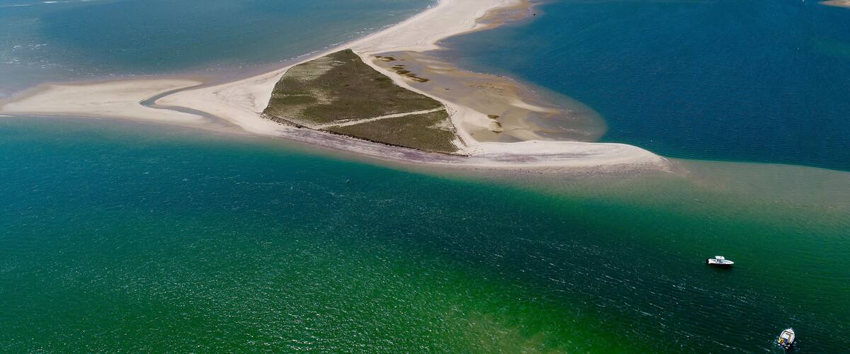 A coastal landscape with a prominent sandy peninsula surrounded by turquoise waters.