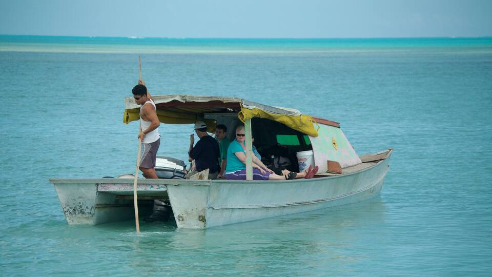 A small boat with people on it, floating on calm turquoise water.