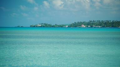 A turquoise sea with a small island in the distance.