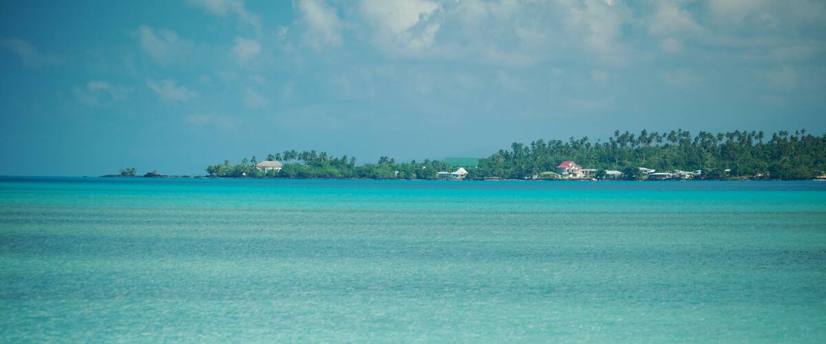 A turquoise sea with a small island in the distance.