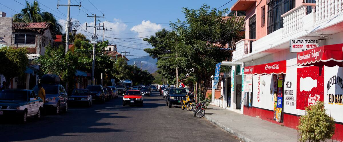 A street with parked cars, a bicycle, and a building with a Coca-Cola sign.