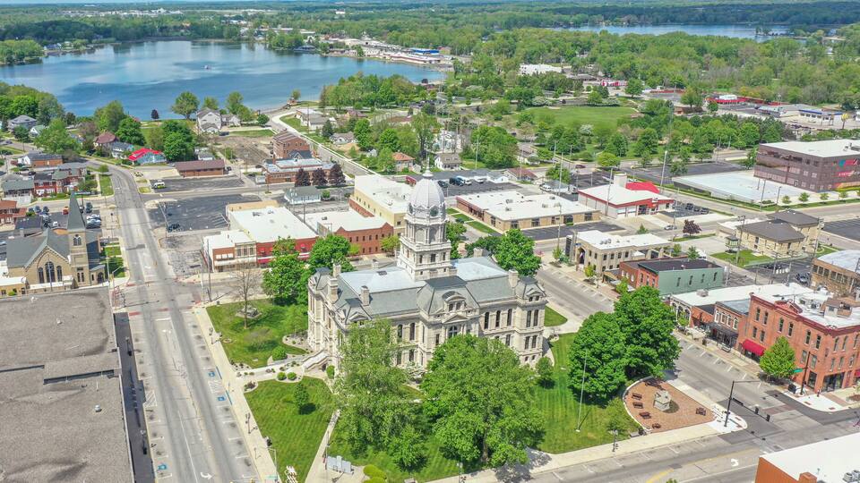 A town with a prominent historic building, a large body of water, and surrounding greenery.